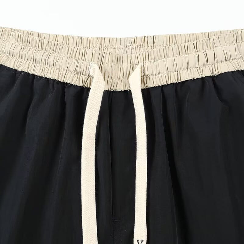 Shorts en nylon décontractés pour hommes, coupe droite, noirs, avec une ceinture élastique beige et des cordons assortis.