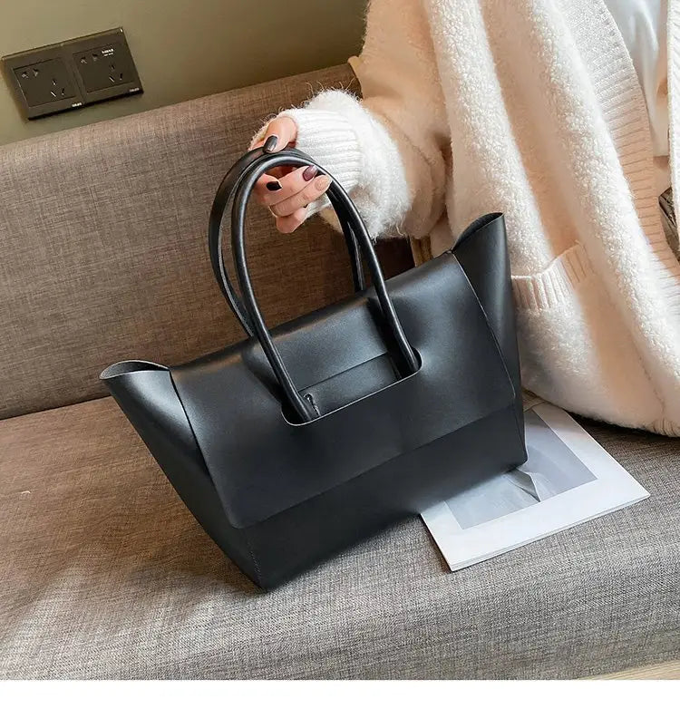Black leather tote bag with structured minimalist design and dual top handles for versatile use.