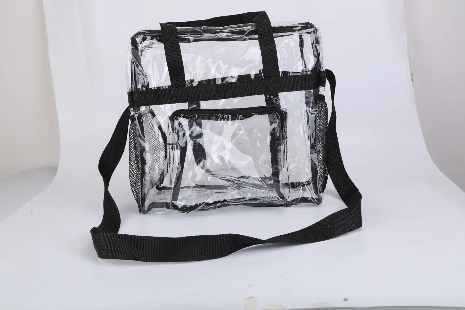 Stadium approved clear crossbody bag with clear plastic body, black mesh sides, reinforced handles, and a detachable shoulder strap.