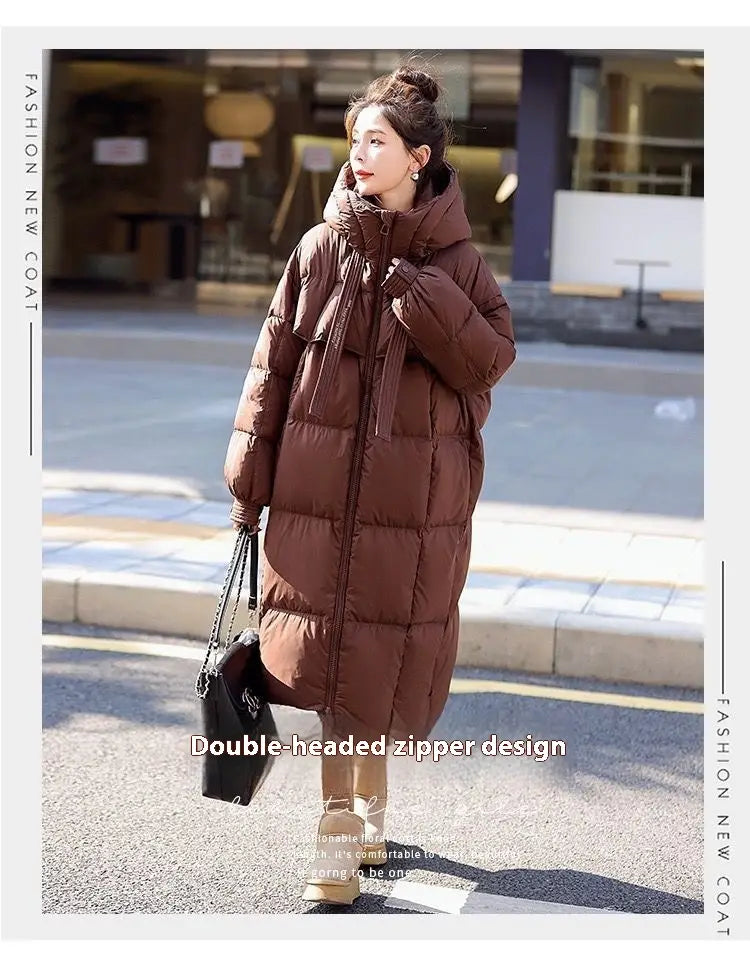 A long brown hooded women puffer coat featuring a double-headed zipper design.