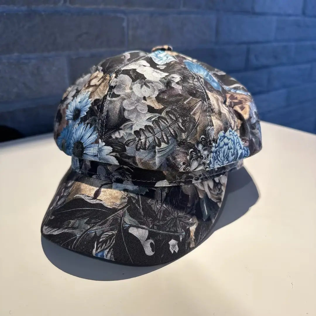 A black fabric floral newsboy cap for women featuring a detailed pattern in shades of blue white and brown.