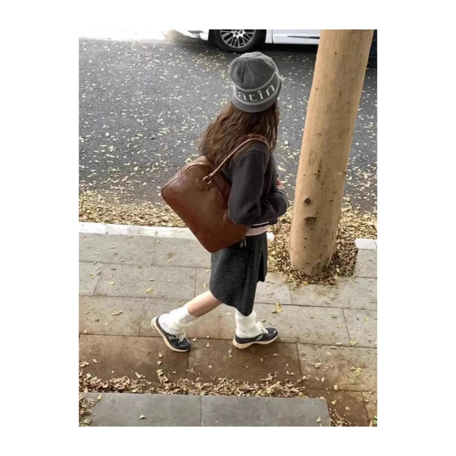 Brown leather shoulder bag with structured shape, visible stitching details, large capacity, and bear charm.