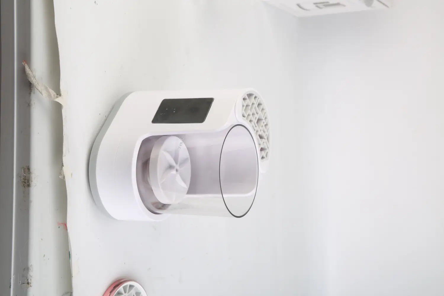 White wall-mounted electric makeup brush cleaner uv sterilizer and dryer with a transparent cylindrical filter housing and a digital display panel.