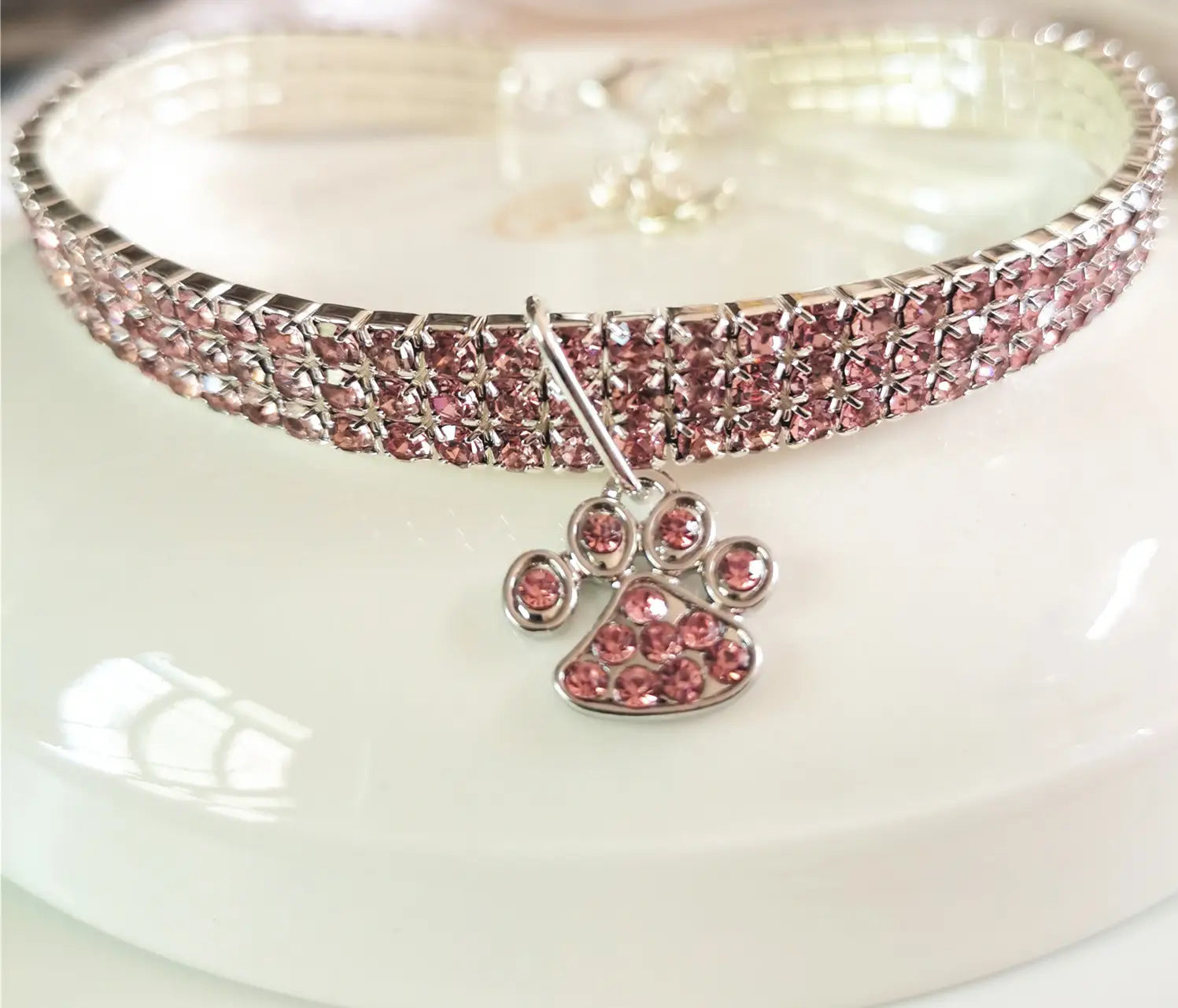 Collier pour chien en strass roses fabriqué dans un matériau durable, avec un charme assorti en forme de patte rose pour une tenue élégante de l’animal de compagnie.