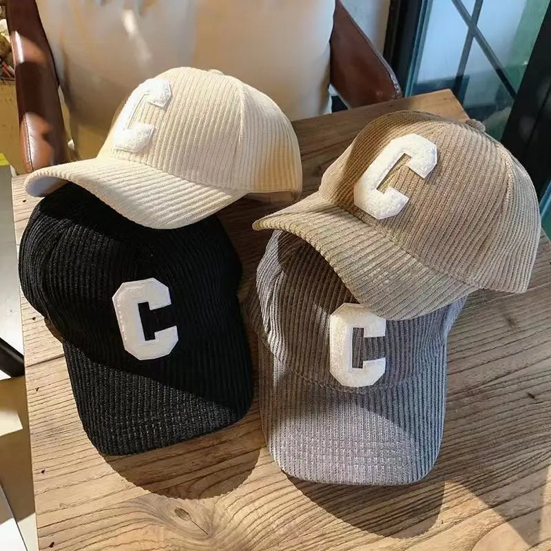 Three corduroy letter c baseball caps in cream black and gray featuring white embroidered c lettering.