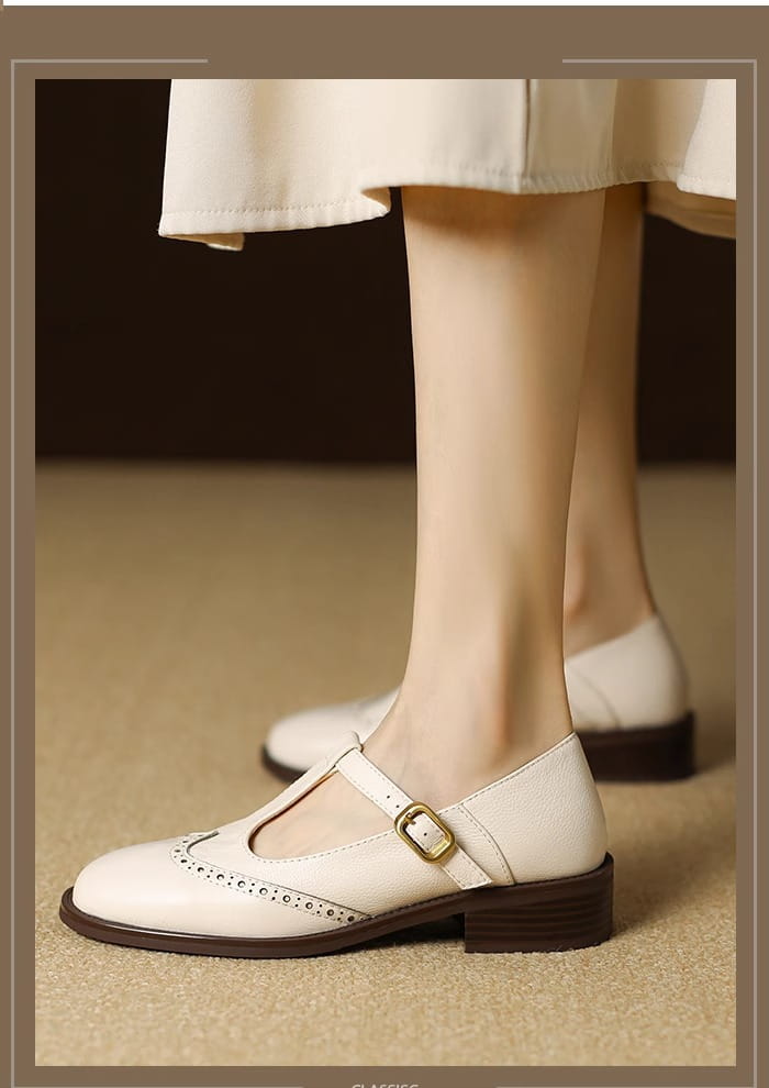 Cremefarbene Leder-Brogue-Mary-Jane-Pumps mit klobigem Absatz mit goldfarbenem Schnallenverschluss und dunkelbraunen Sohlen.