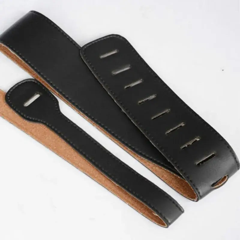 Black leather guitar strap with a smooth matte finish and contrasting tan suede lined adjustable inner lining measuring 110 to 130 centimeters.