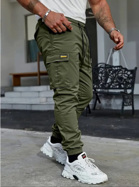 Men’s slim fit cropped olive green cargo joggers with drawstring waist and multiple pockets featuring a small black label on the thigh pocket.