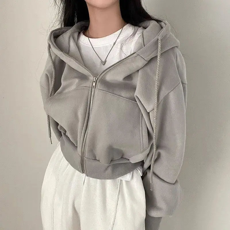 Ein weicher, hellgrauer, verkürzter Zip-up-Kapuzenpullover mit Kapuze und Kordeln, gezeigt von der Rückseite, im Produktstil eines dunkelblauen Samt-Velours, wattierten Kapuzenpullovers mit schmaler Passform.