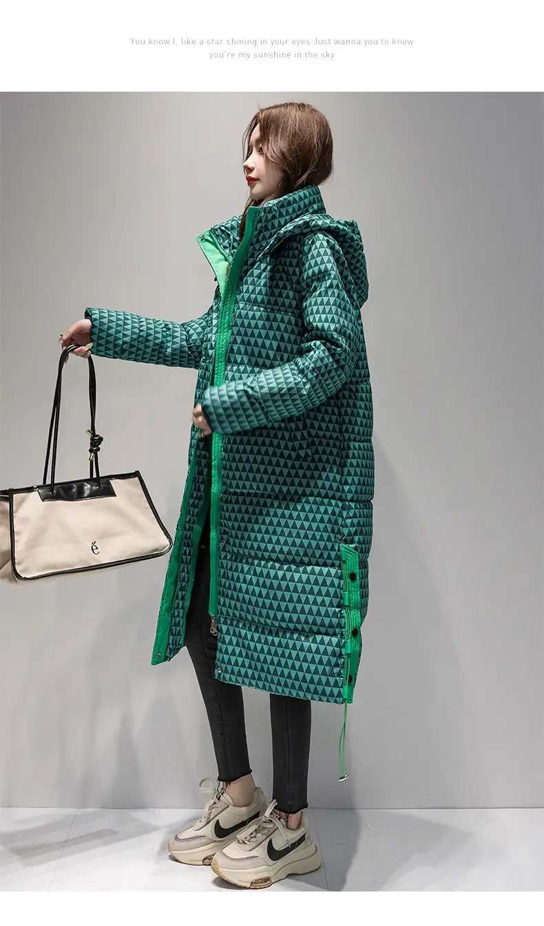 Un long manteau matelassé vert en coton pour femmes avec un motif de triangle géométrique et une capuche assortie, arborant un style pied-de-poule.