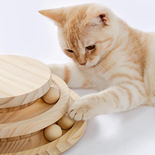 Griffoir pour chat en bois clair brun, avec corde en sisal et piste à balle, comprenant des plateaux circulaires empilés et de petites billes sphériques.