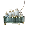 A teal green glass 360 rotating makeup organizer with vertical ridges and gold legs holding white and clear bottles
