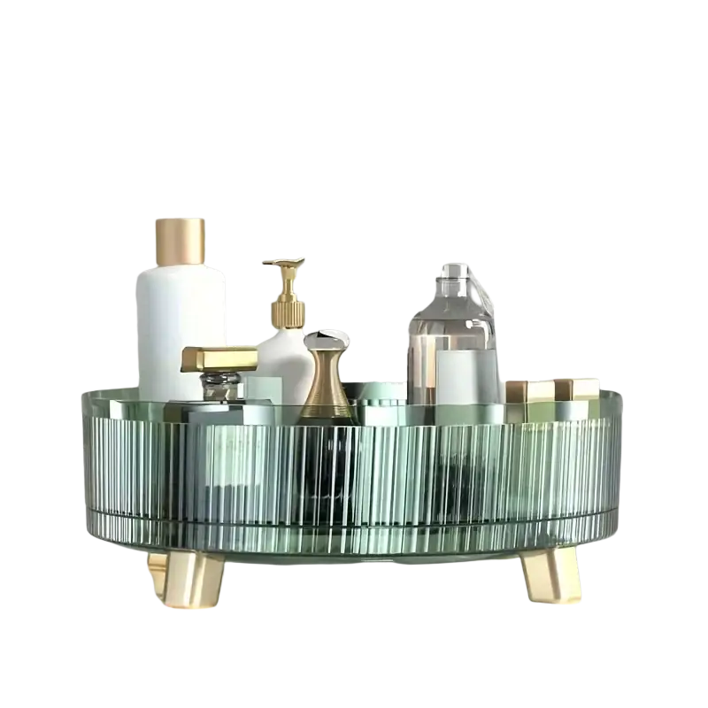 A transparent oval glass 360 rotating makeup organizer tray with vertical ridges and gold-tone legs for bathroom essentials