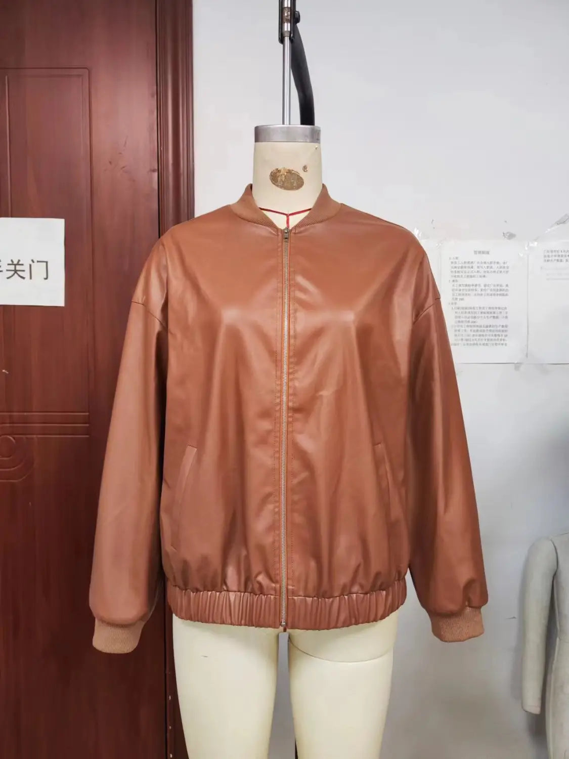 A sleek tan faux leather bomber jacket with a matte finish and ribbed cuffs.