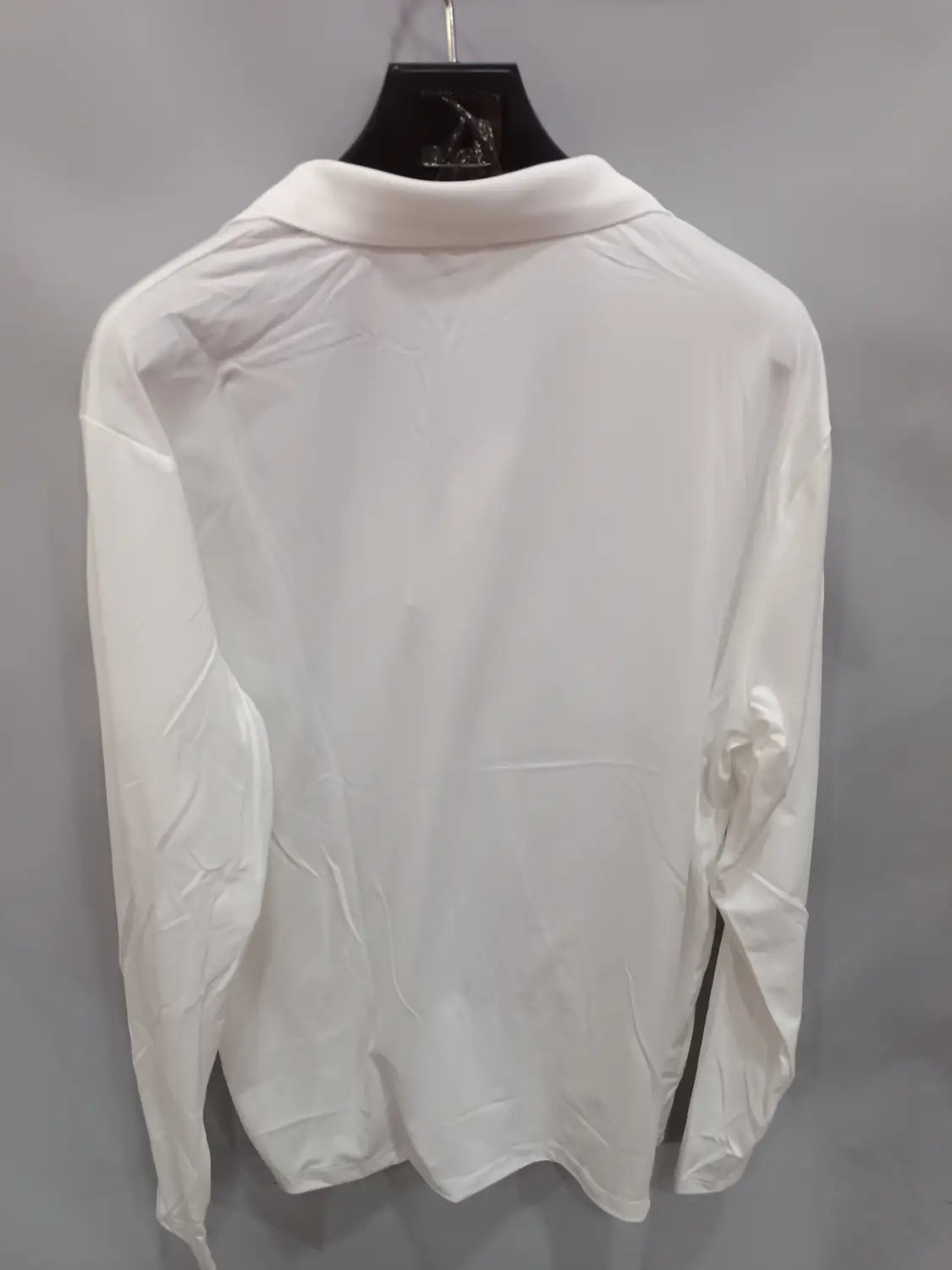 Ein frisches weißes langärmliges Polohemd im Casual-Sporttop-Stil mit klassischem Kragen, ordentlich an einem schwarzen Kleiderbügel hängend.