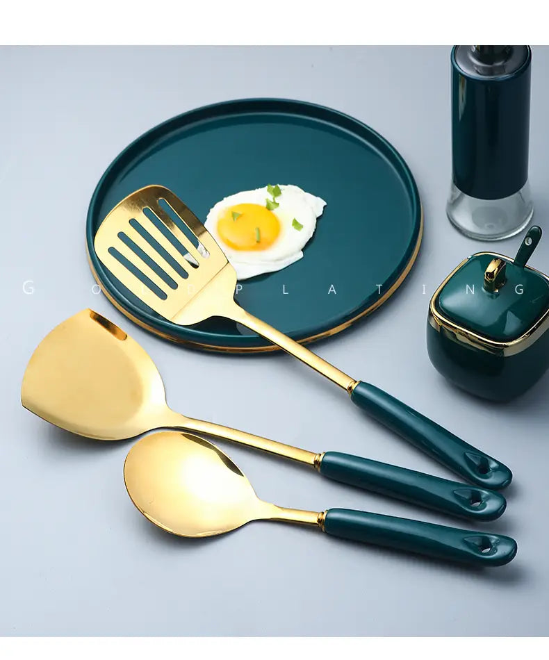Drei Edelstahl-Küchenutensilien mit goldener Oberfläche und dunkelgrünen Griffen zum Kochen und Servieren.