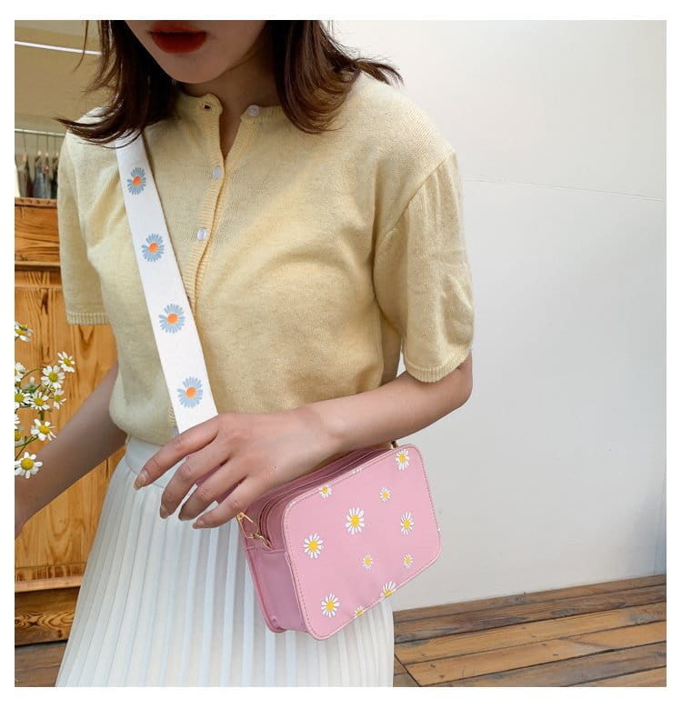pink daisy-patterned pu leather crossbody bag with white adjustable strap featuring matching floral design and chain strap accents