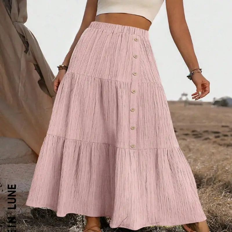 A soft pink tiered maxi skirt with a gathered waist button closure lightweight and casual for everyday wear.