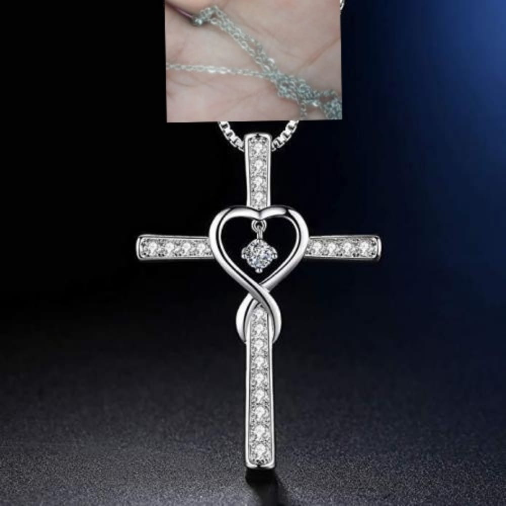 Silver cross pendant with heart-shaped infinity knot design featuring clear sparkling crystals along its arms and center in an infinity love heart cross birthstone crystal necklace.