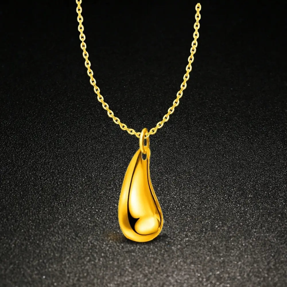 Goldfarbene tropfenförmige anhänger-kette mit einer eleganten polierten oberfläche und einer zarten kette, dargestellt in einem modernen silbernen tropfenförmigen schmuckset mit gemischten accessoires.