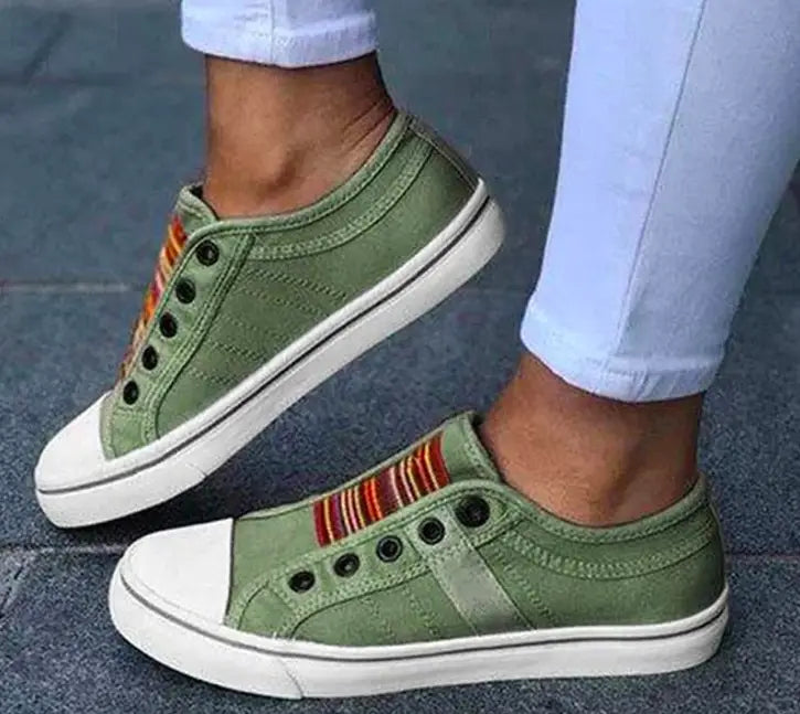 Olivgrüne schnürlose Canvas-Sneaker zum Hineinschlüpfen mit weißen Gummisohlen und einem farbigen gestreiften Akzent an der Seite.