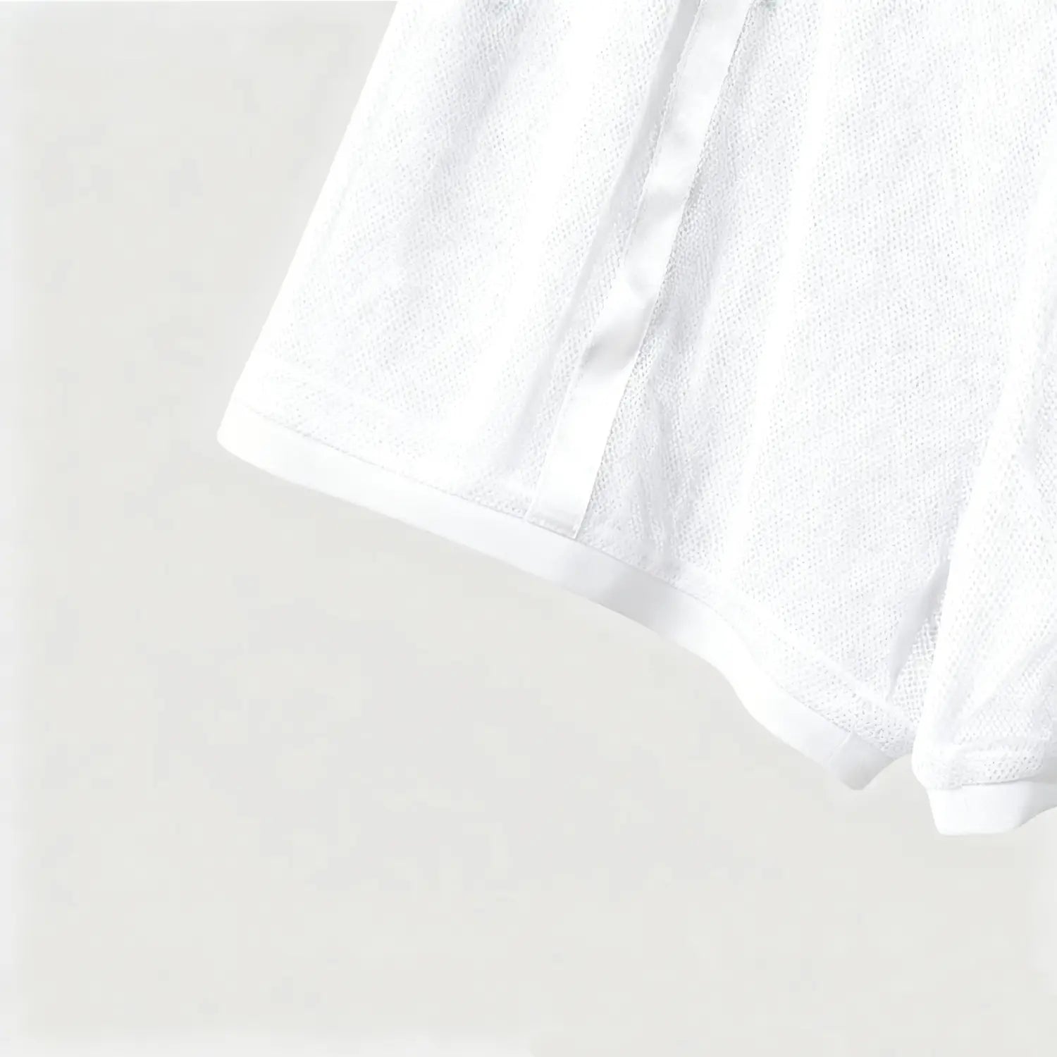 White cotton terry cloth towel with a soft textured surface and neatly finished edges alongside men quick dry white mesh athletic shorts.