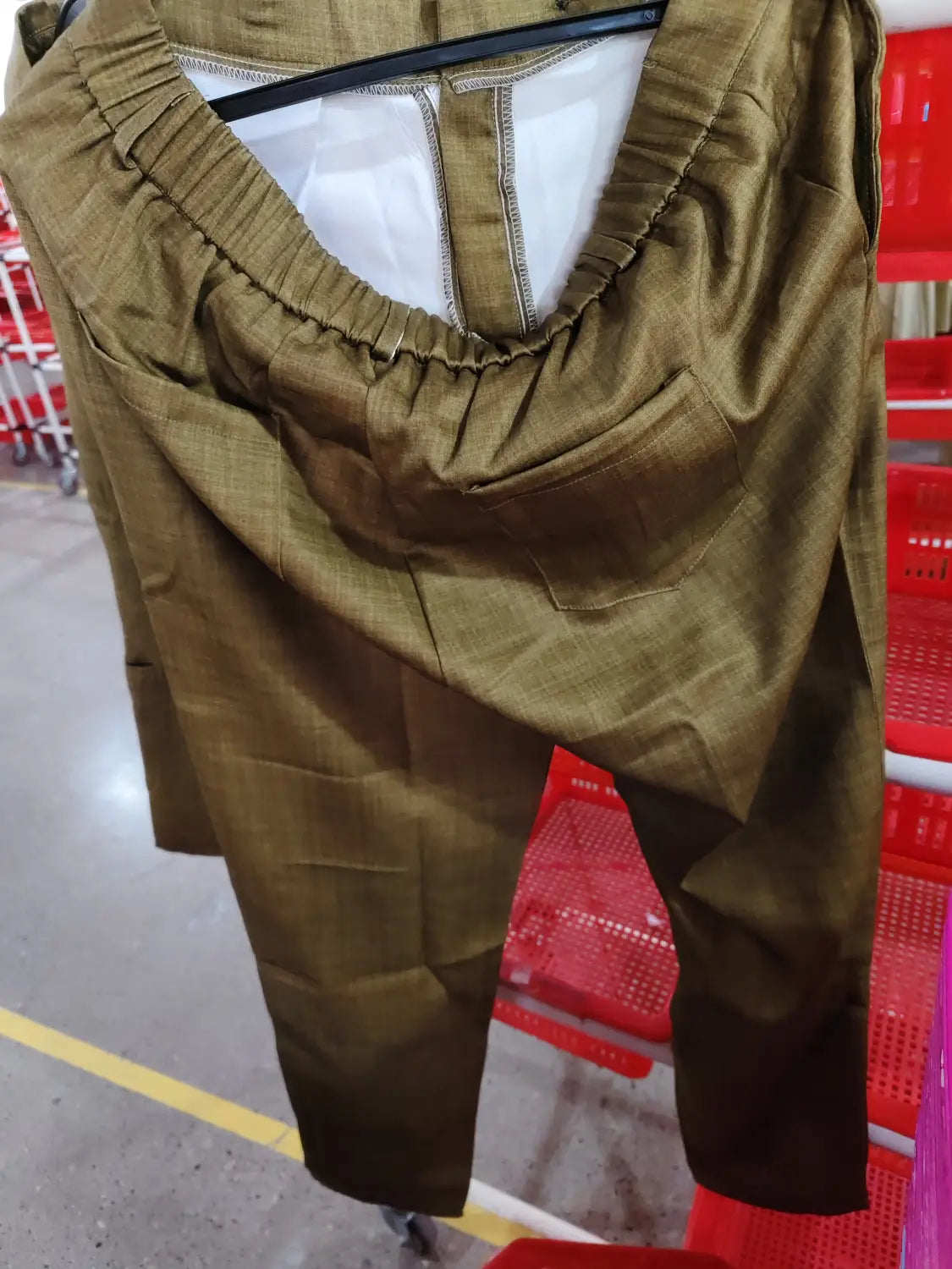 Pantalones color verde oliva con textura, con cinturilla elástica y pliegues sutiles, como parte de un traje digital de dos botones.