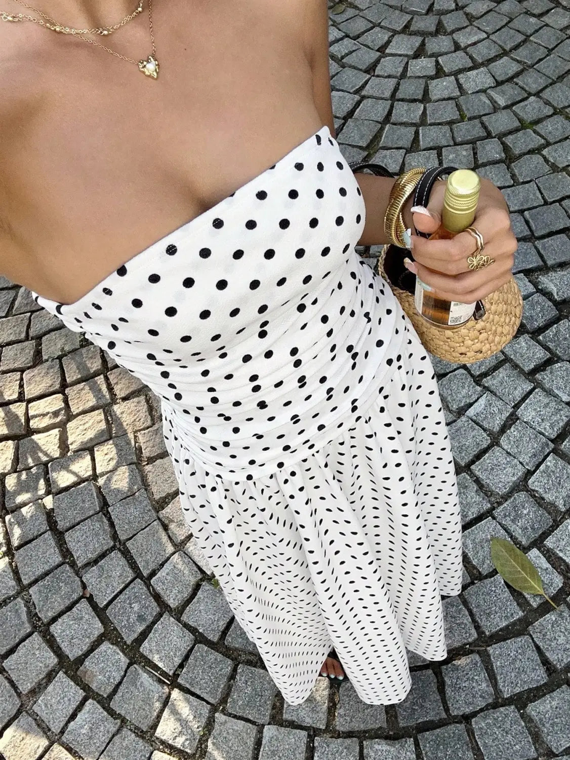 White strapless maxi dress with black polka dots featuring an off shoulder design, ideal for formal and casual occasions.