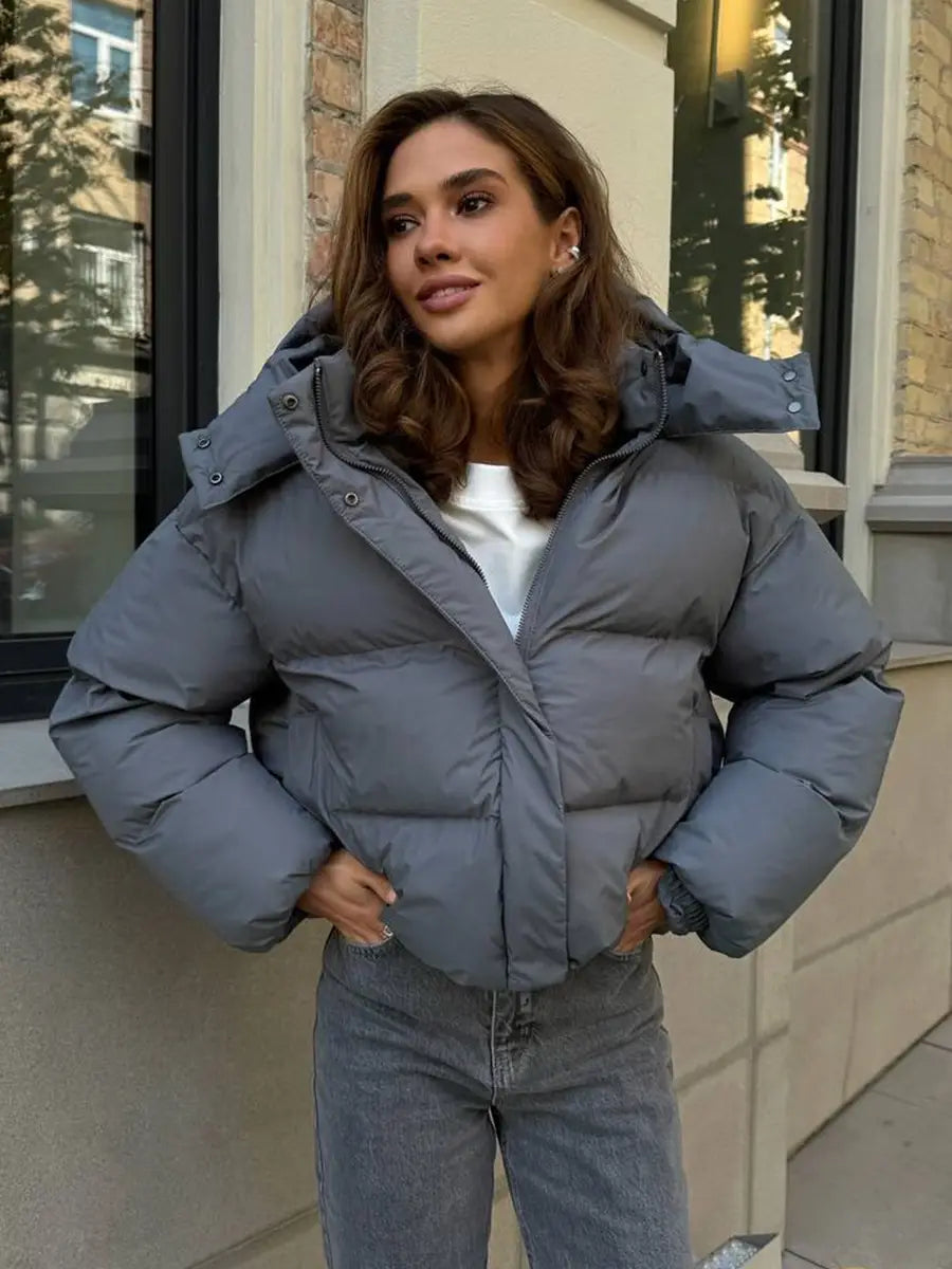Graue wattierte Pufferjacke mit Kapuze mit einem warmen, isolierenden Design, ideal für kaltes Wetter.