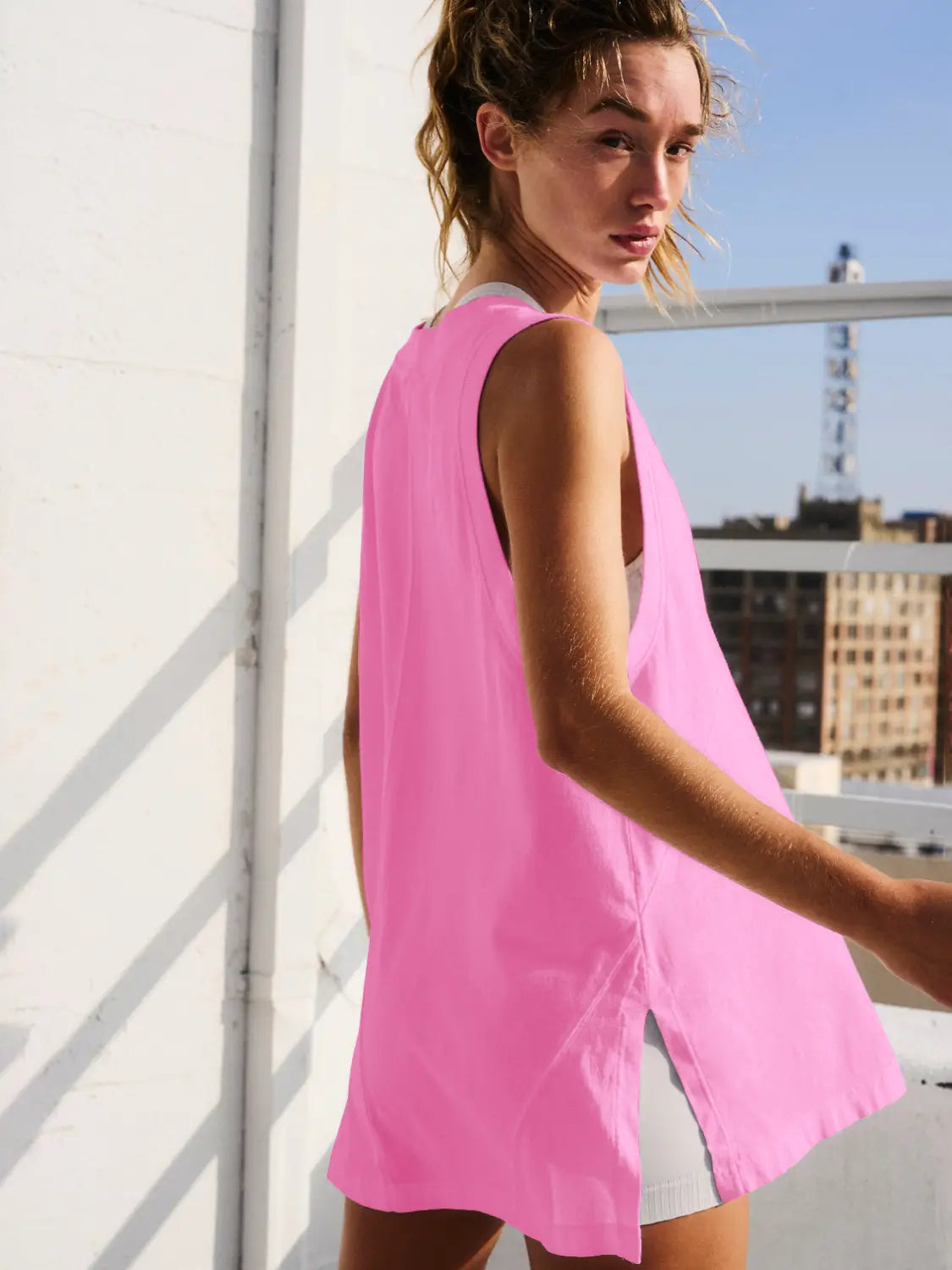 A vibrant pink sleeveless cotton wrap vest top featuring a relaxed v neck fit and side slit made from lightweight fabric.
