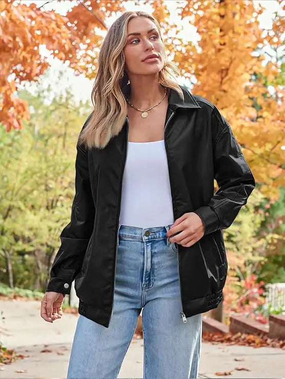 Black faux leather bomber jacket oversized relaxed fit coat with a sleek glossy finish and ribbed cuffs shown from the back side.