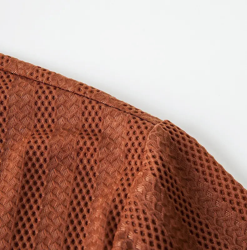 A rust-colored mesh fabric with a textured diamond-patterned weave used in a men’s textured ice silk contrast trim polo shirt.