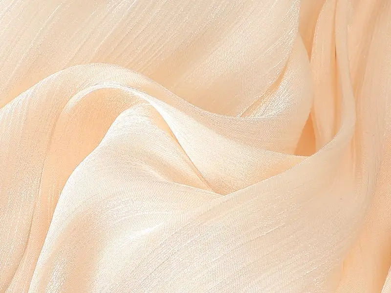 ein zartes Chiffontuch in Pfirsichfarbe mit dezentem Schimmer und weich fließenden Falten, das den irrisierenden Chiffon-Faltenrock ergänzt