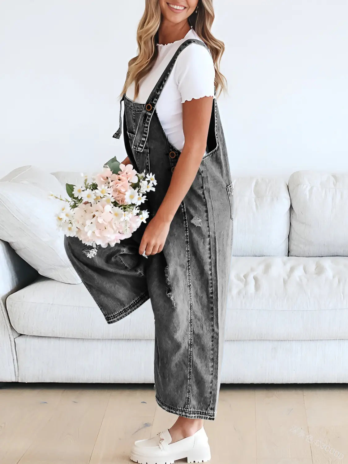 Black denim overalls for women with a distressed faded finish and adjustable straps.