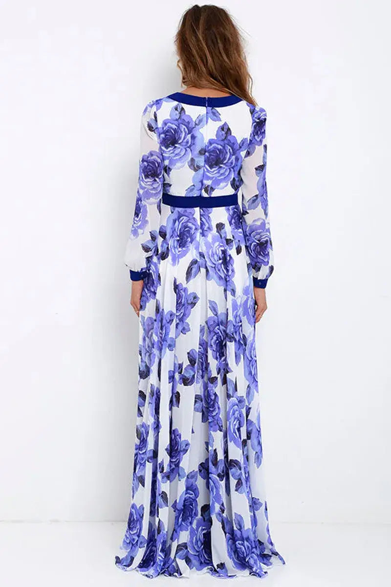 A flowing white vintage blue floral v-neck maxi dress adorned with a vibrant purple rose print and navy blue trim along the neckline, cuffs, and waistband.