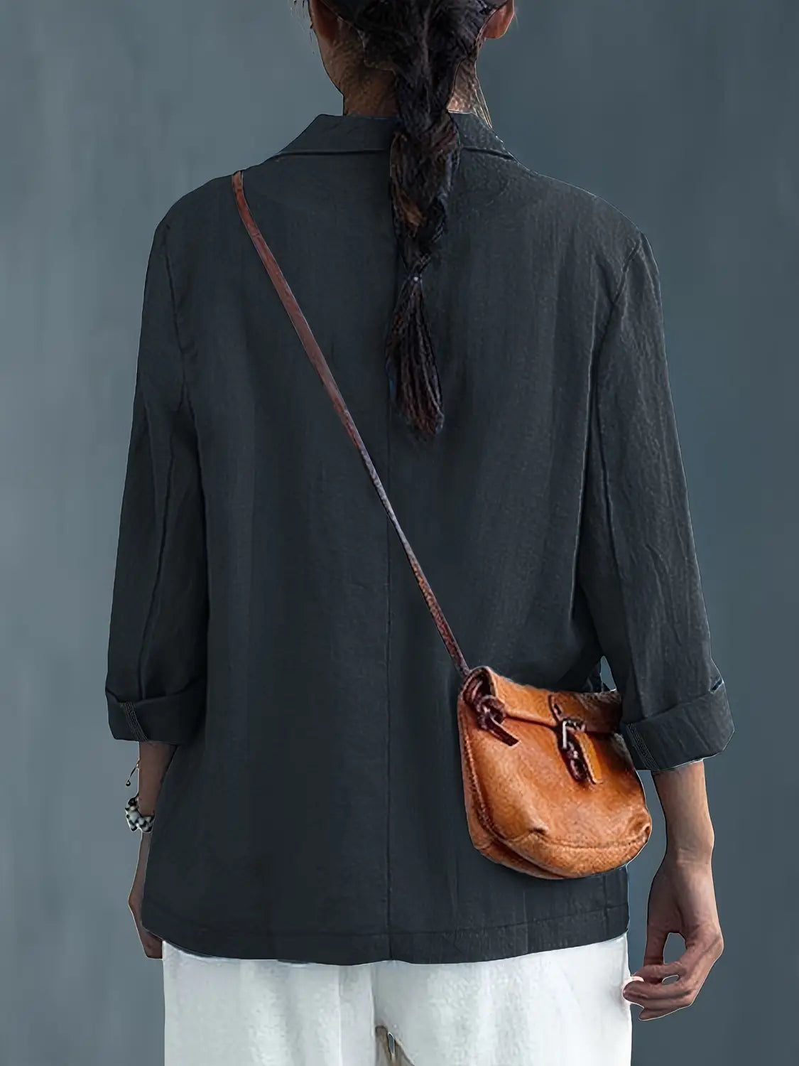 Un bolso cruzado de cuero color camel con cierre de hebilla y correa a juego, mostrado junto con un blazer de lino para mujer, casual y de trabajo.