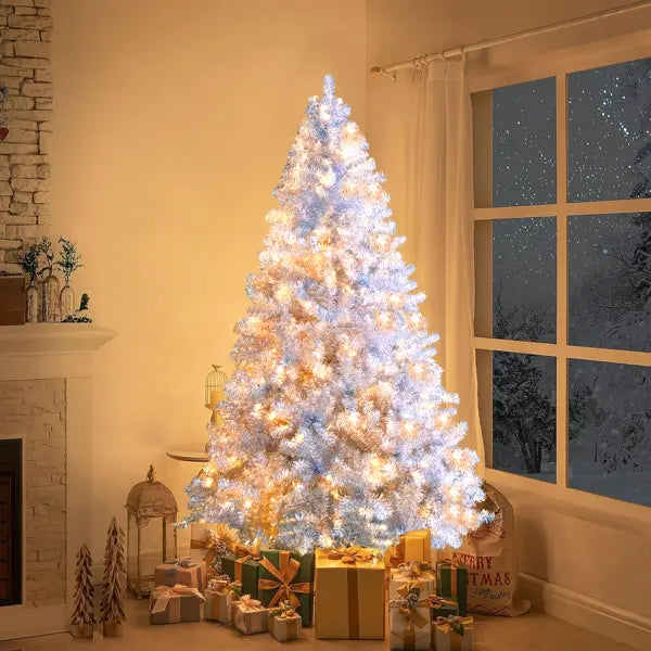 A tall white silver pre-lit artificial christmas tree with LED lights and frosted texture stands centered in the room.