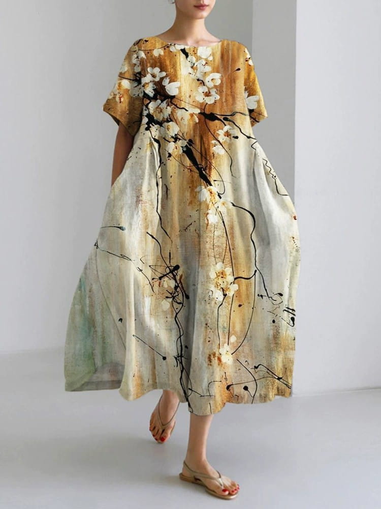 Artistic printed loose linen maxi dress in soft beige and gold with an abstract floral pattern featuring white blossoms and black brushstroke accents.