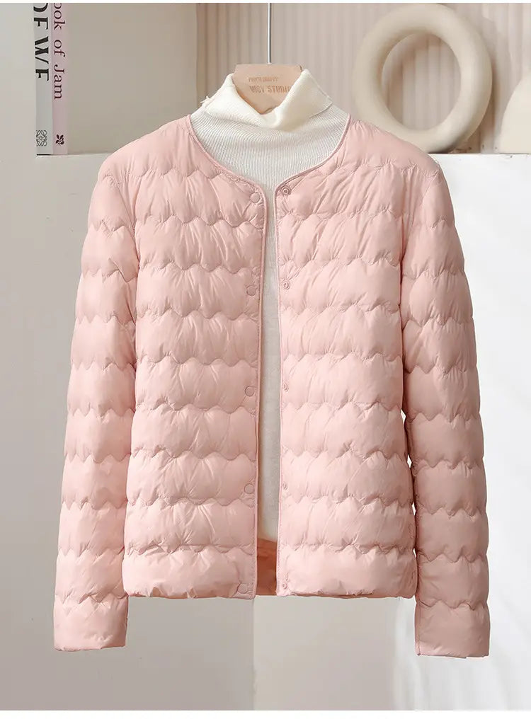 A soft pink quilted puffer jacket with a ruffled crew neck rounded collar and button closure.