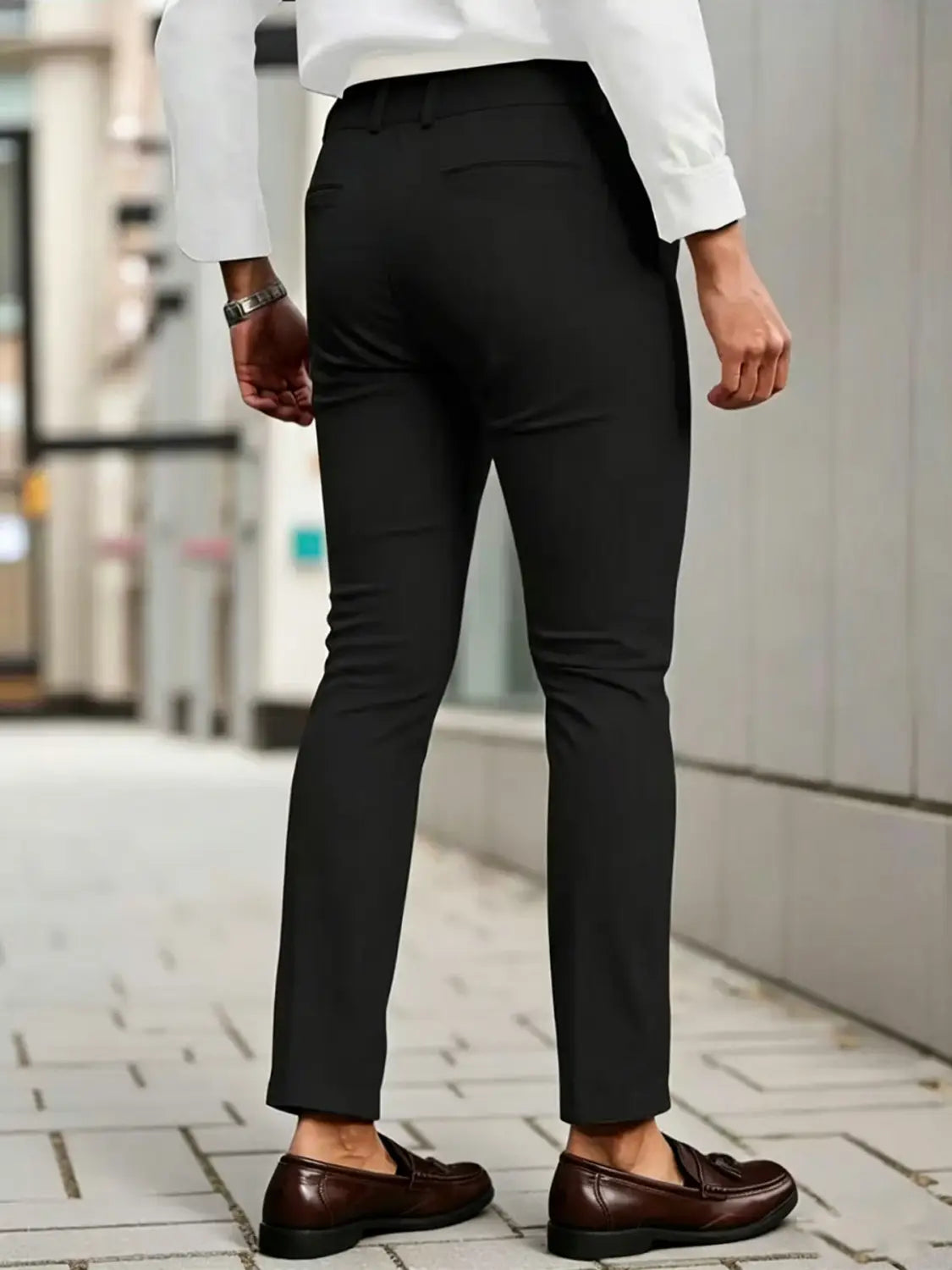 Herren-Slim-Fit-Stretch-Anzughosen in Schwarz mit maßgeschneiderter Passform und dezenten Falten, getragen mit braunen Lederloafern.