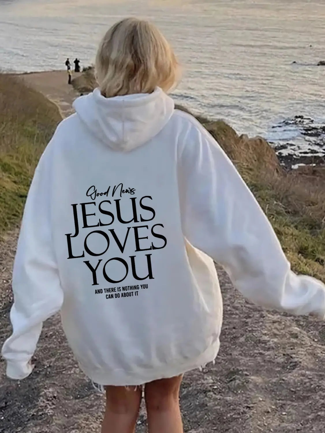 white oversized streetwear kangaroo pocket hoodie made of soft fabric featuring jesus loves you printed in black text on the back side