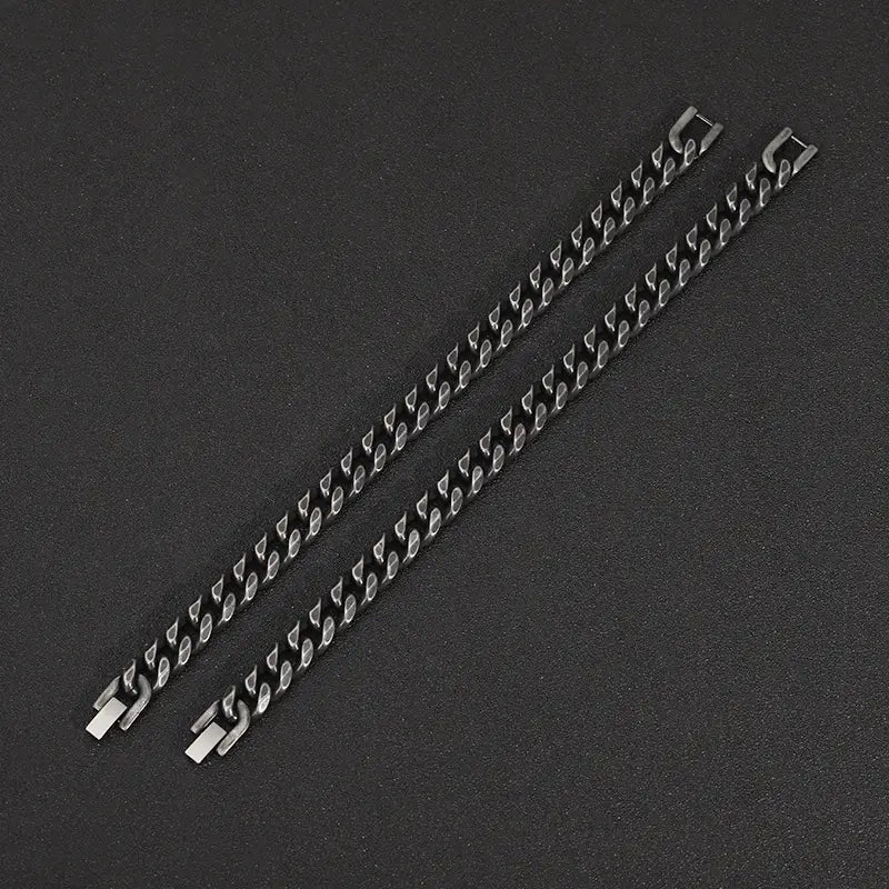 Two sleek matte black stainless steel curb chain bracelets with polished silver-toned clasps displayed on a white background.