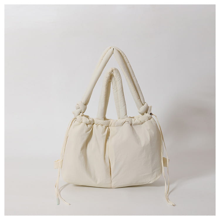 Cream-colored quilted canvas tote bag with padded knotted handles and drawstring closure lightweight nylon shoulder bag.
