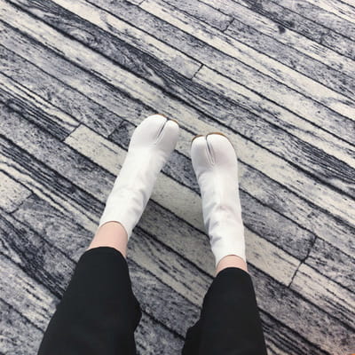 white tabi socks with a distinct split toe design made from smooth leather like material featured in split toe tabi high heel leather ankle boots.