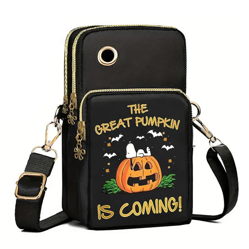 Black halloween-themed crossbody phone bag featuring gold zipper accents and a cartoon pumpkin design with Snoopy and the text the great pumpkin is coming in yellow lettering.