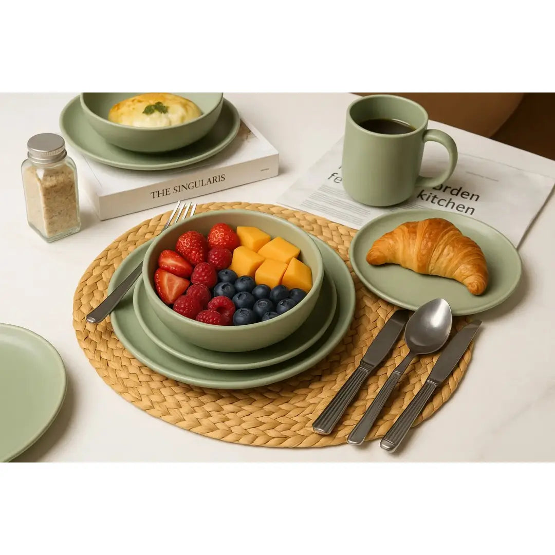 Ein 12-teiliges Steinzeug-Geschirrset in matter Salbeigrünfarbe mit einer Schüssel sowie Tellern und einer Tasse mit glatten Keramikoberflächen für vier Personen