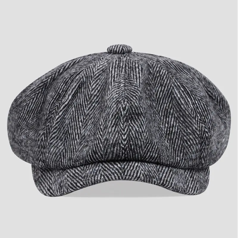 A classic gray herringbone-patterned woolen flat cap with a rounded crown and structured brim in the style of a herringbone tweed flat cap octagonal beret.