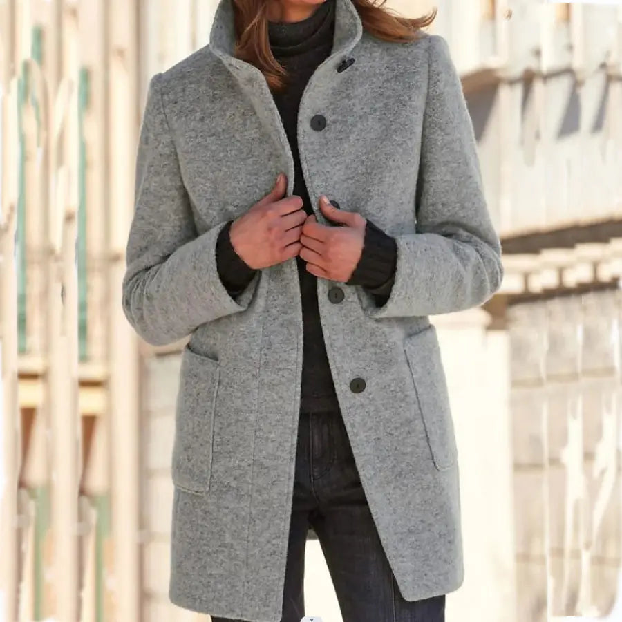 Ein stilvoller grauer Woll-Turtleneck-Mantel aus Wollmaterial mit klassischem Kragen und schwarzen Knöpfen in einfarbigem Retro-Jacken-Design.