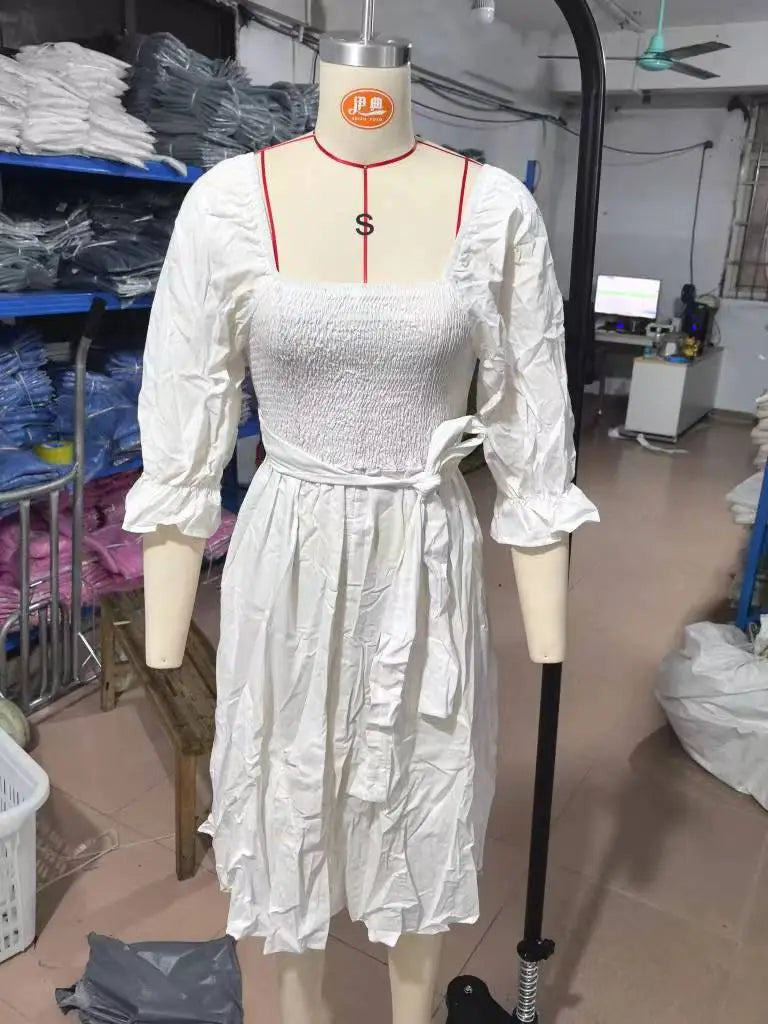 white smocked midi dress with v-neck, puffed lantern sleeves, and a tied waistband.