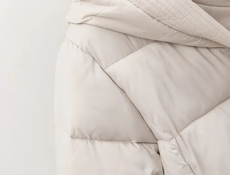 A soft off-white women quilted hooded winter puffer coat with smooth slightly shiny fabric and clean stitching along padded sections.
